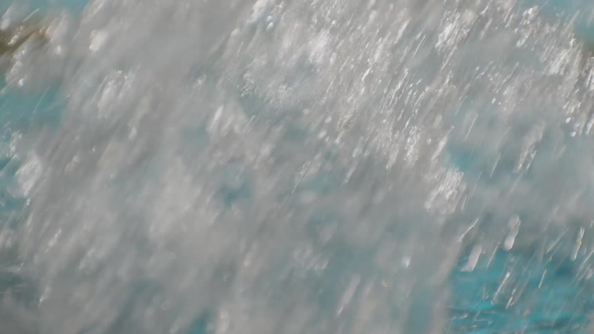 A swimmer in propels through a pool water splashing around as their arm cuts through the water