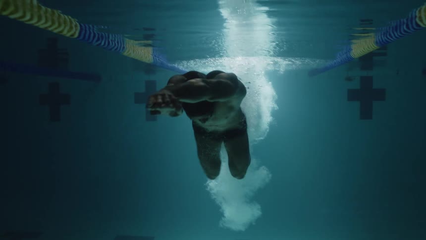 A man dives into the pool and swims