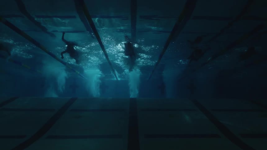 Swimmers dive in to pool and swim underwater