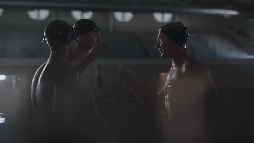 Three male swimmers greeting and hugging each other