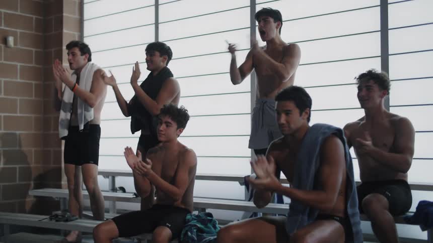 A group of shirtless men with towels around their necks are clapping their hands in celebration