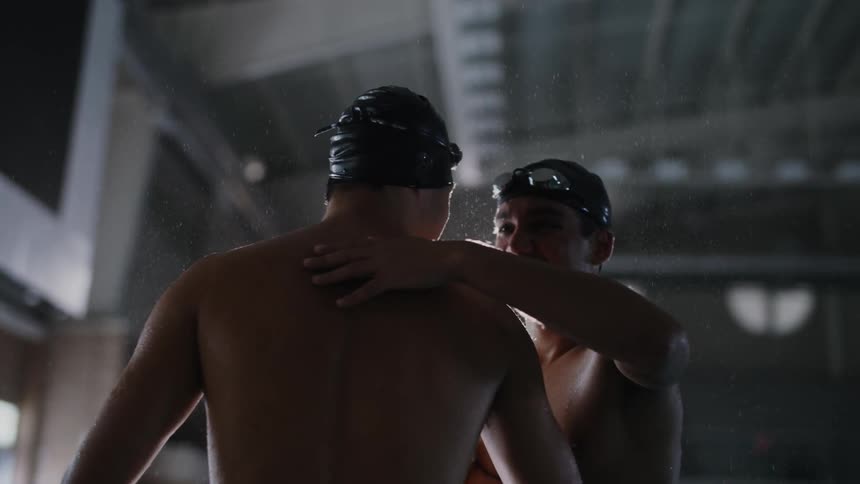 Two young swimmers clapping hands and hugging happily