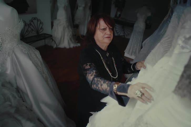 A woman is searching through wedding dresses in the shop