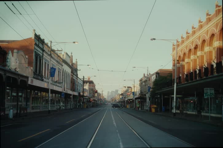 A street view with tram lines running down the center flanked by twostory buildings with ornate facades under a clear sky