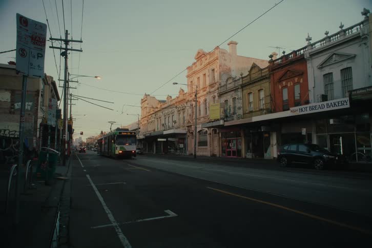 A tram travels down the street in a small town at dusk