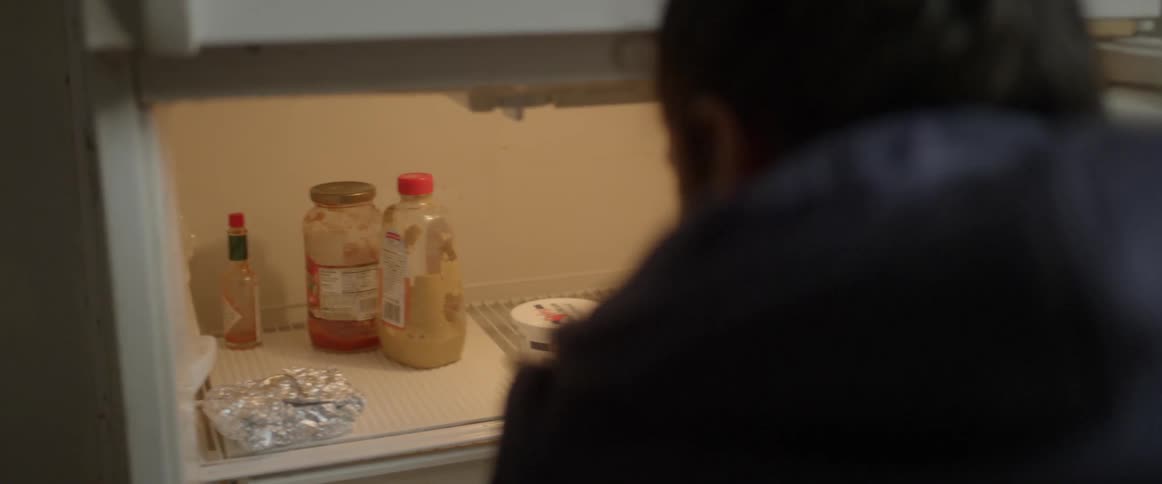 A woman looks through her fridge for food