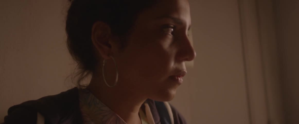A woman with dark hair swallows and looks up before walking away