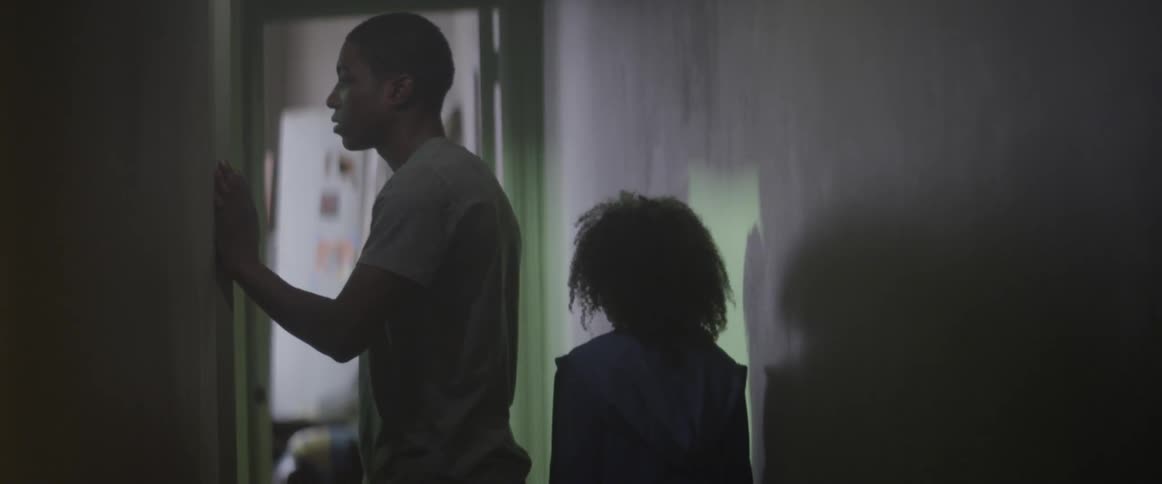 A man and young girl are walking down the hallway of a building