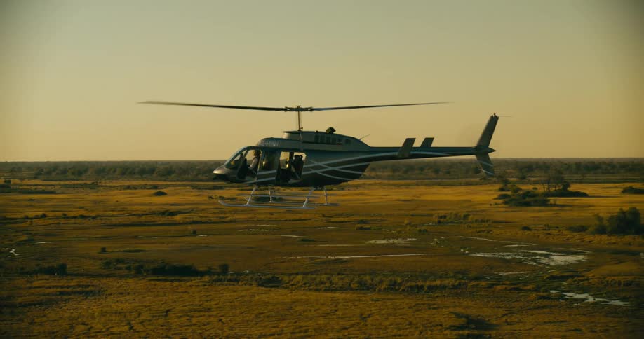 A helicopter flies over a vast grassland