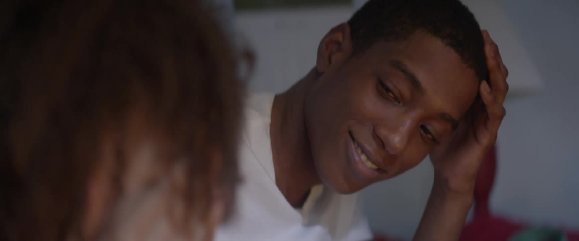 A teenage boy smiles and looks at a young girl in a room