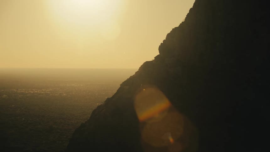 The silhouette of a mountain on the left side and a strong sunlight coming from the morning sky