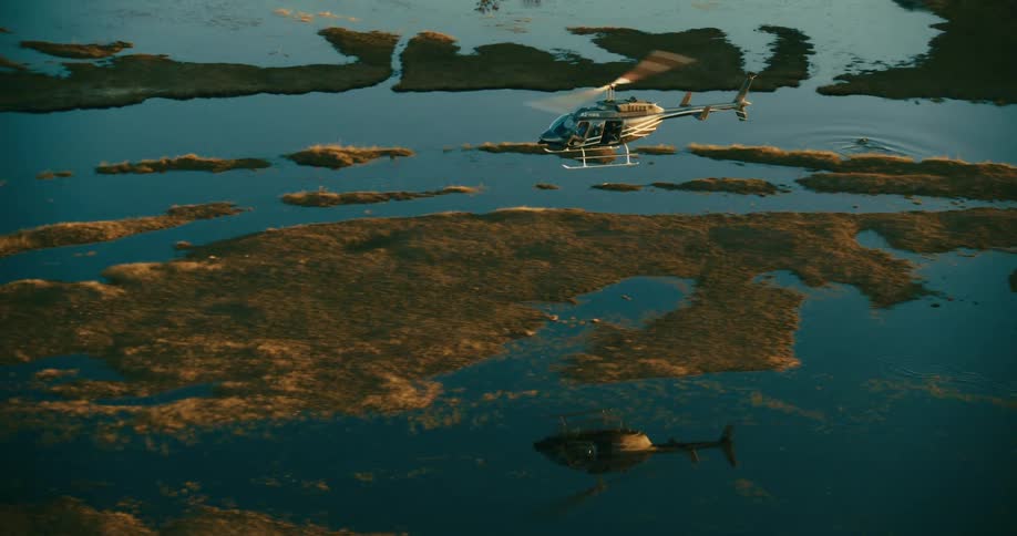 A helicopter flying over a marshy area with many puddles of water