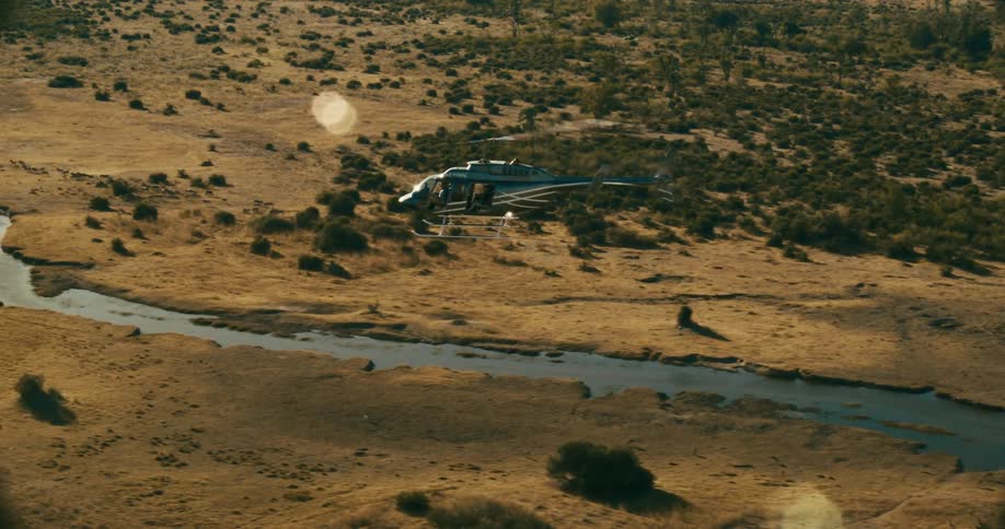 A helicopter over a savanna following a river