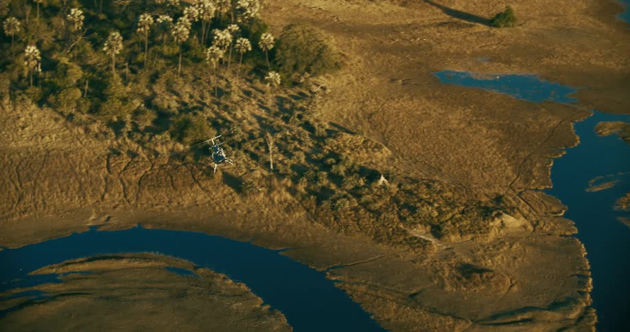 Aerial panorama of a helicopter flying above a green area with water