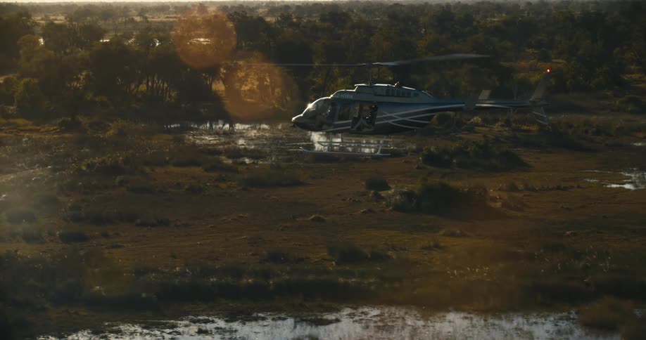 Helicopter flying in a jungle area with the sun reflecting on the horizon