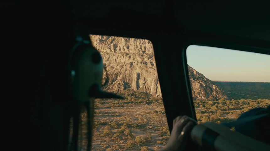 A woman pilots an aircraft near a mountain on a coast