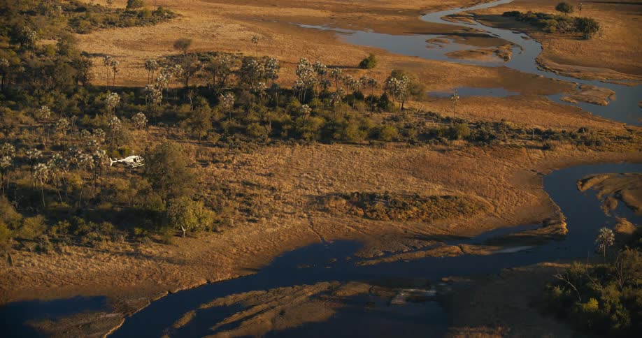 A helicopter flying over a natural region with beige soles and a river