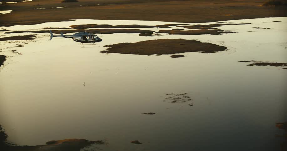 Aerial view of a helicopter flying above a lake in a jungle
