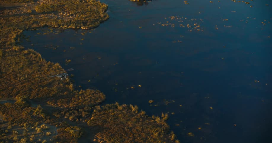 Aerial panorama from a helicopter flying over an area with vegetation and a lake