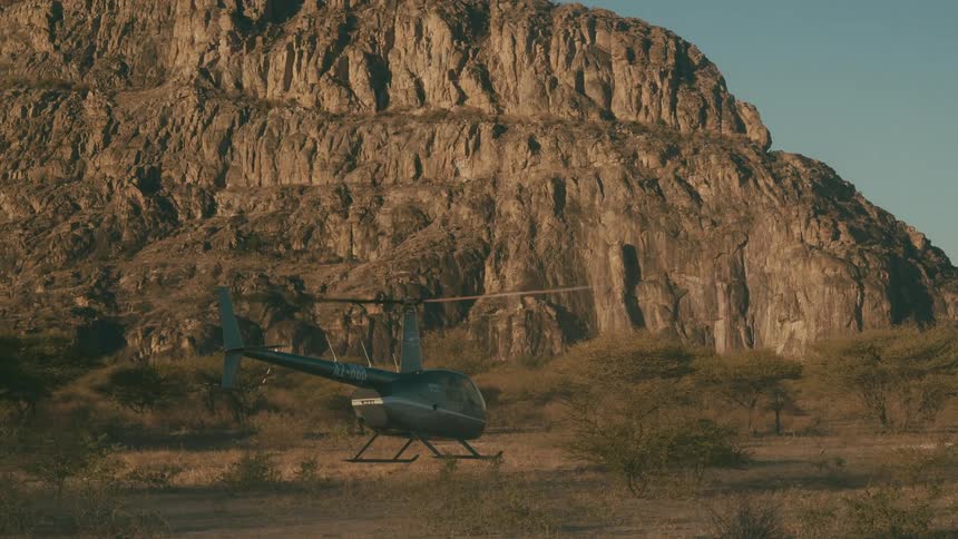 Helicopter landing on a plateau with mountains in the background