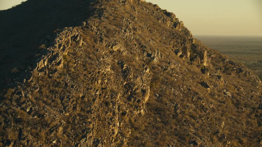 Rugged rocky hill with sparse vegetation illuminated by early morning light