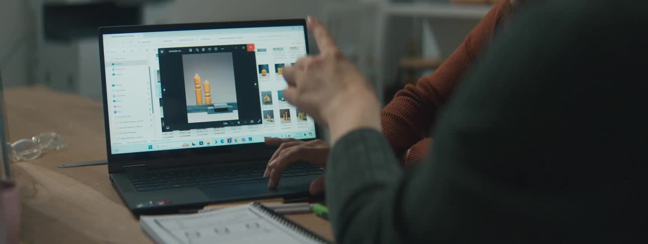 Laptop screen with an open graphic design program and womens hands around it