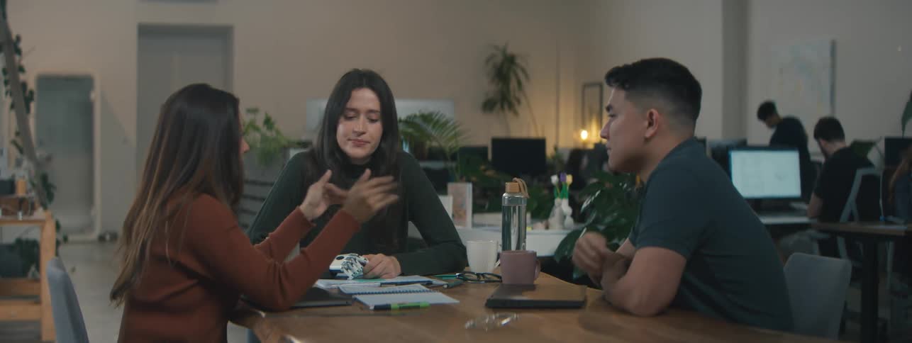 Man and two women sitting at an office table talking