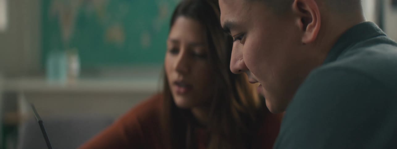 A man and a woman talk while looking at a laptop screen