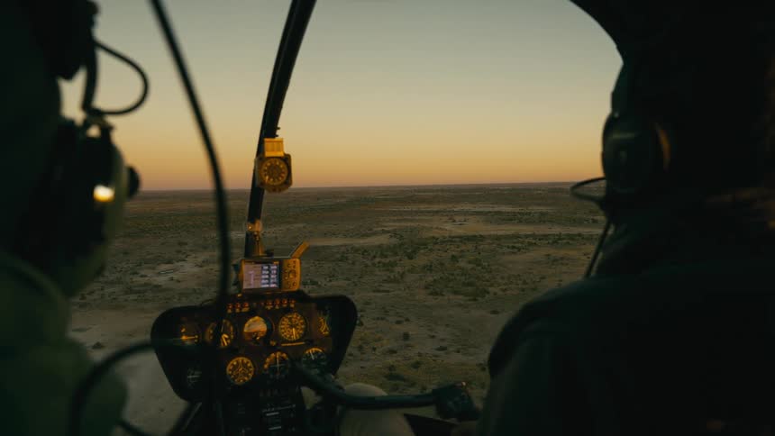 Two pilots and a cockpit in a helicopter with the golden sky on the horizon