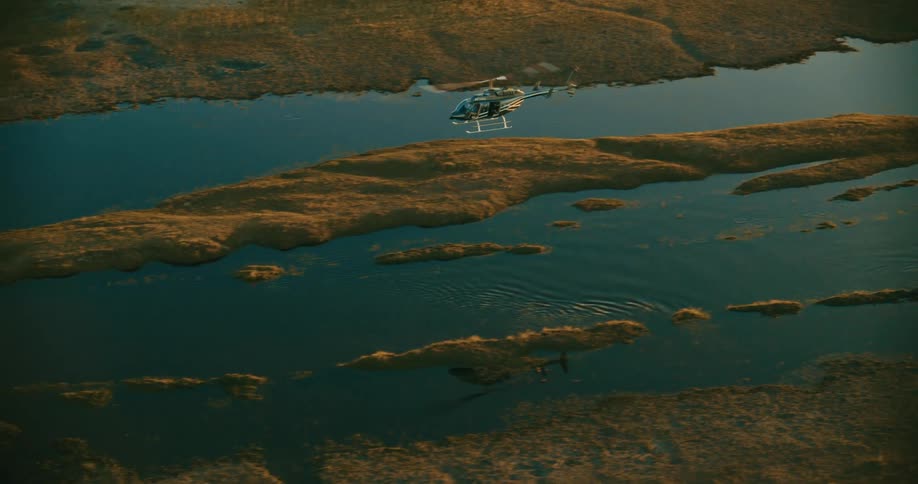 A helicopter flying over a river that is partially dry