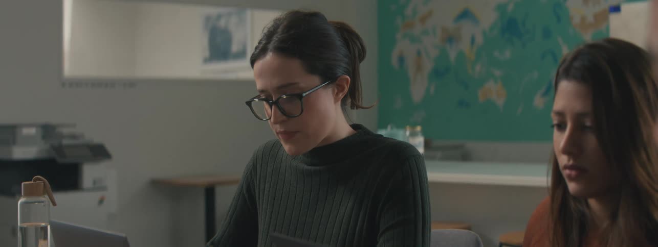 Two women and a man in a work environment focused on their laptop