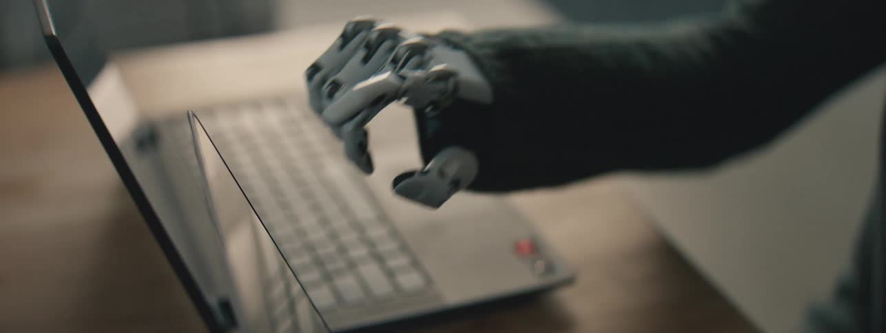 A robotic hand is clicking on a laptop screen