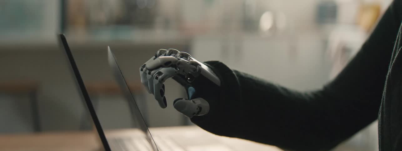 Hand of a robotic person pointing at a laptop screen