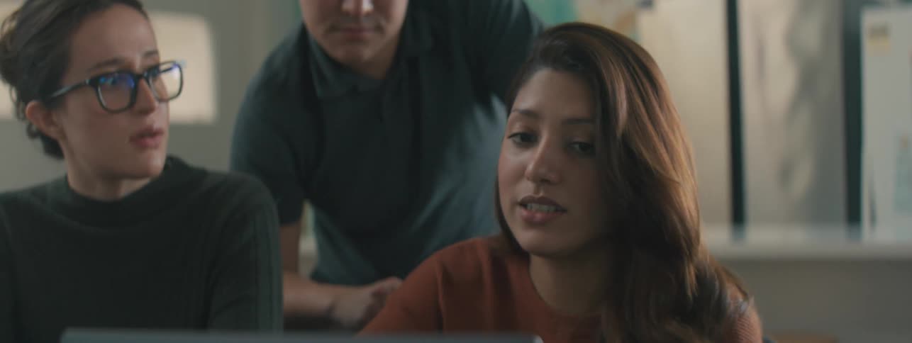Three people in front of a laptop talking