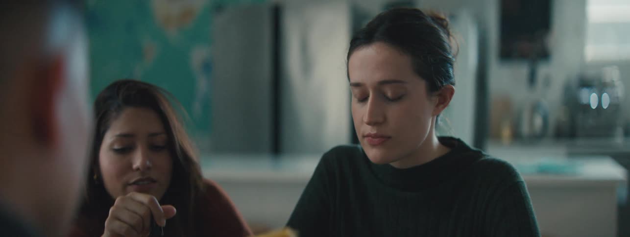 Two women are standing next to each other and talking and someone is in front of them