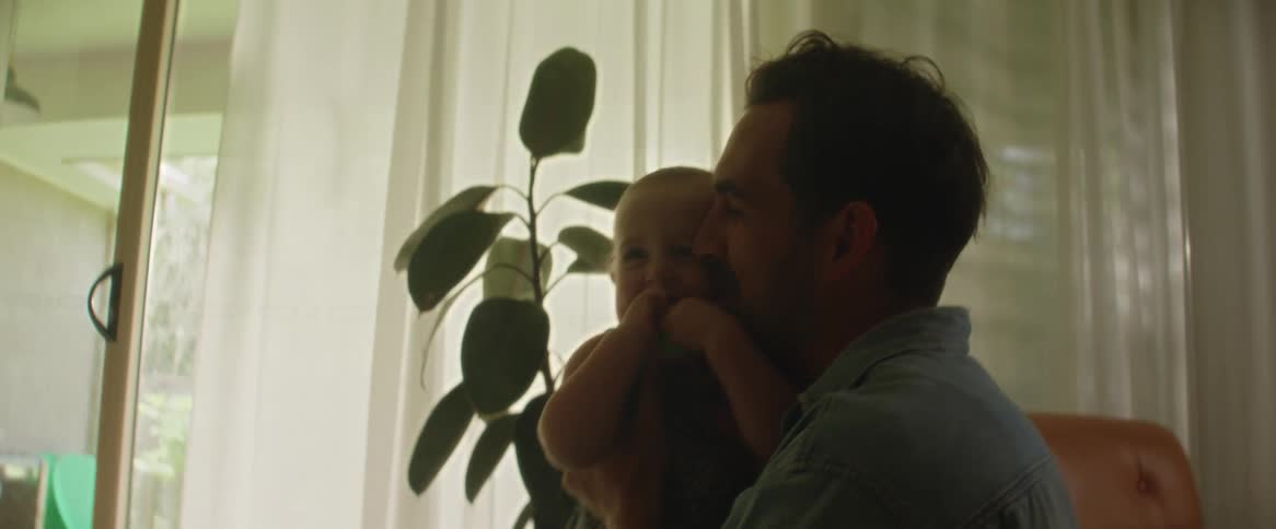 A baby daughter walking from her mother towards her father who happily picks her up in his arms