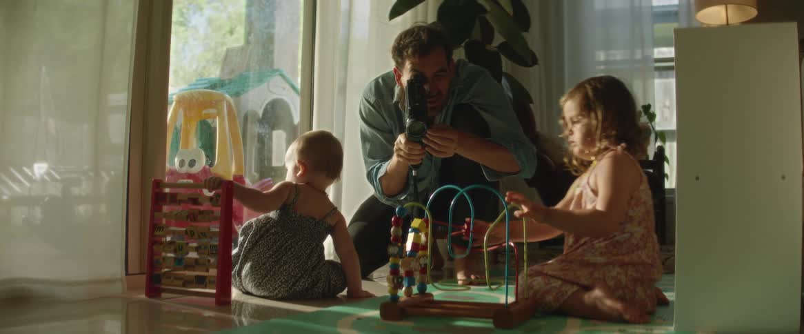 Father records his daughters playing with toys on floor of home