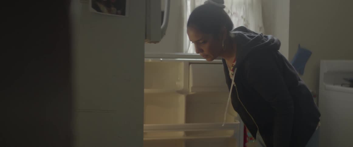 Woman takes something wrapped in foil out of a fridge
