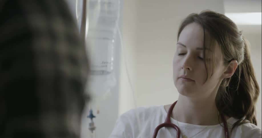 Nurse hooking tubes to an iv fluid bag in hospital