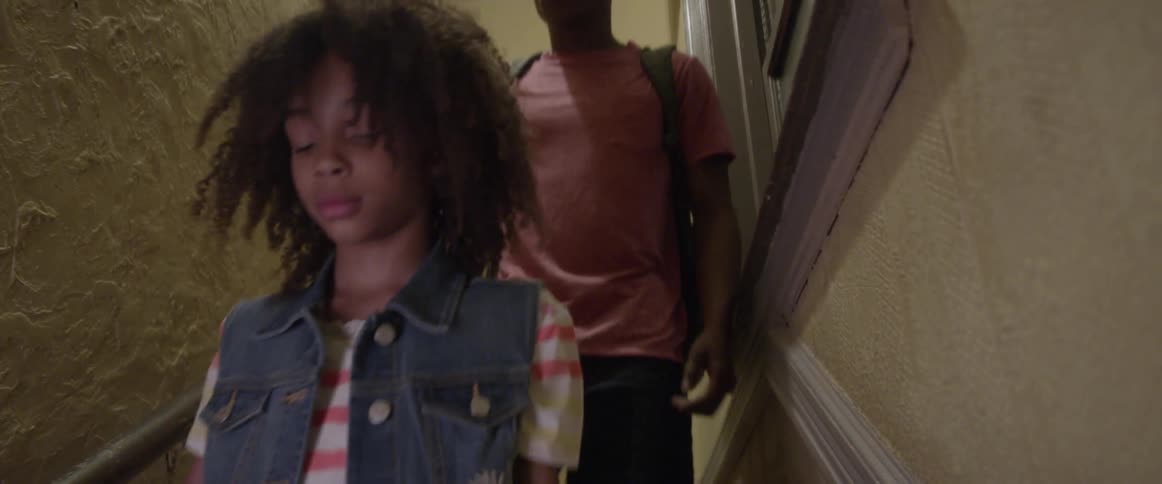Young man and little girl wearing backpacks walk down stairs