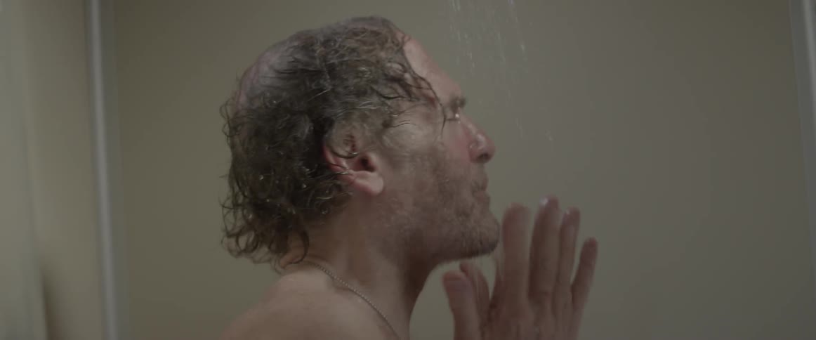 A man in the shower cleaning his face