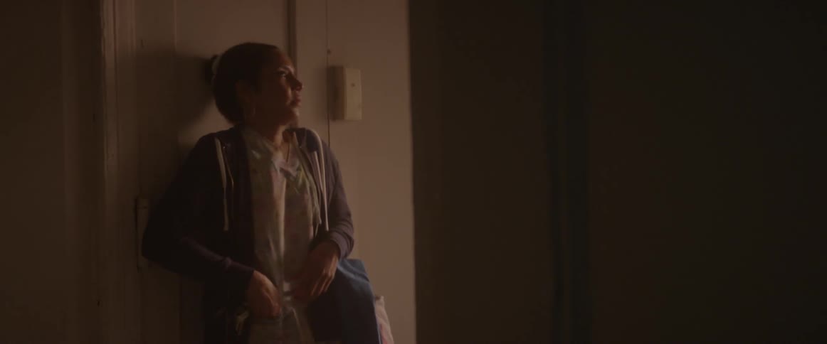A woman walks into her apartment then shuts the door and locks it