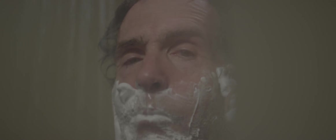 Man shaving his face in the shower