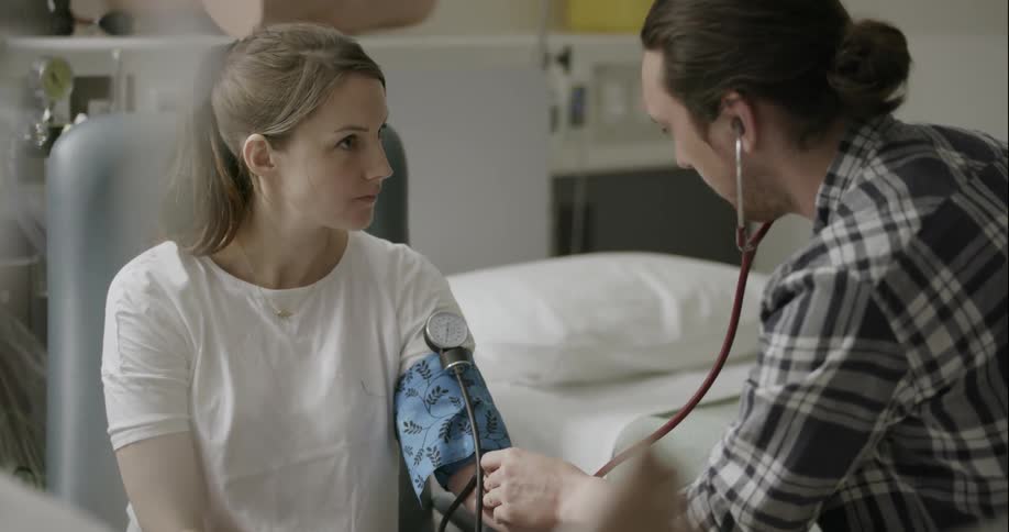 Man taking woman's blood pressure in doctors office