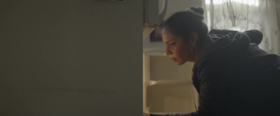 A woman opens up a refrigerator and looks around inside