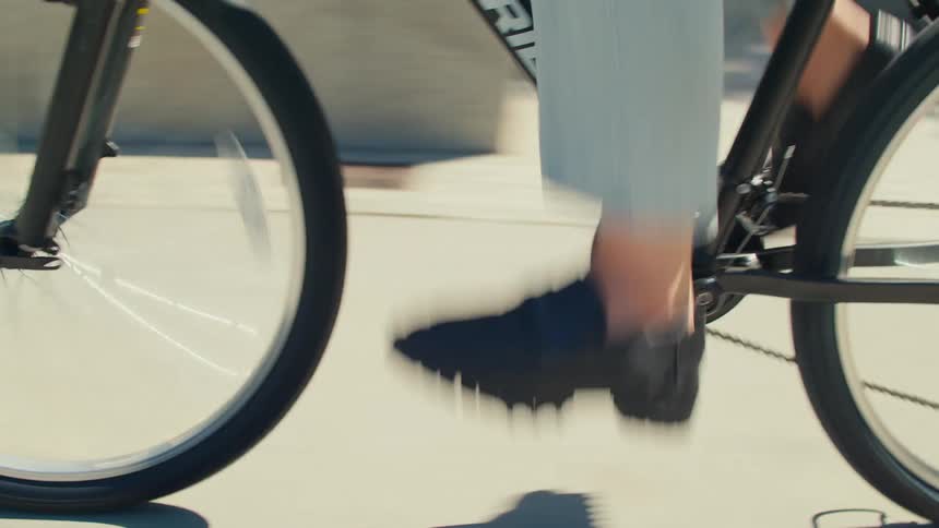 A cyclists legs pedaling a black mountain bike in the city
