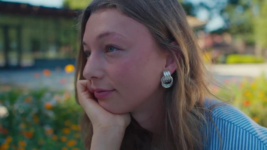 A young woman with long hair is resting her chin on her hand looking thoughtfully while smiling and nodding