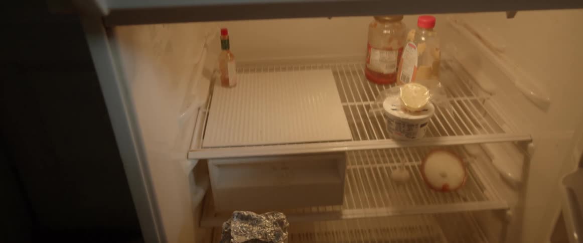 A person removes something from a fridge covered with tin foil