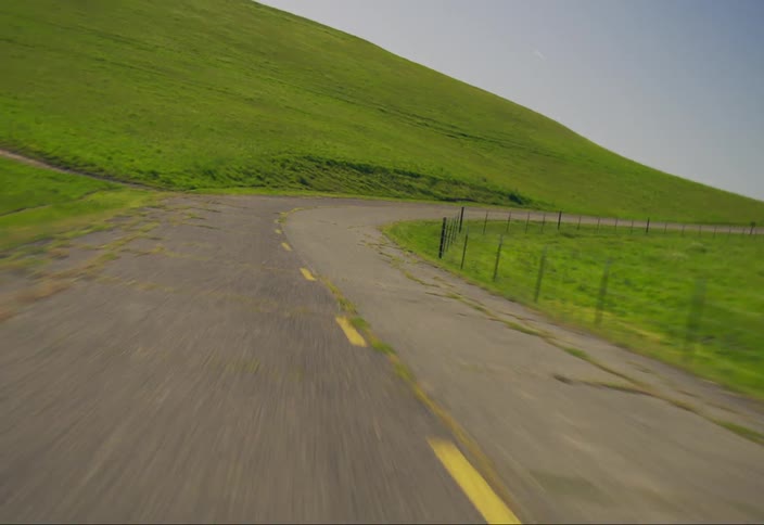A winding road leading uphill through a green valley