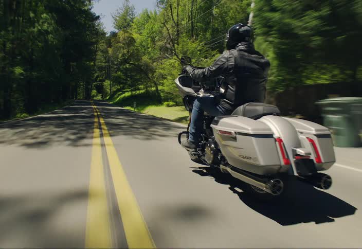 Person riding a motorcycle on a road surrounded by lush vegetation